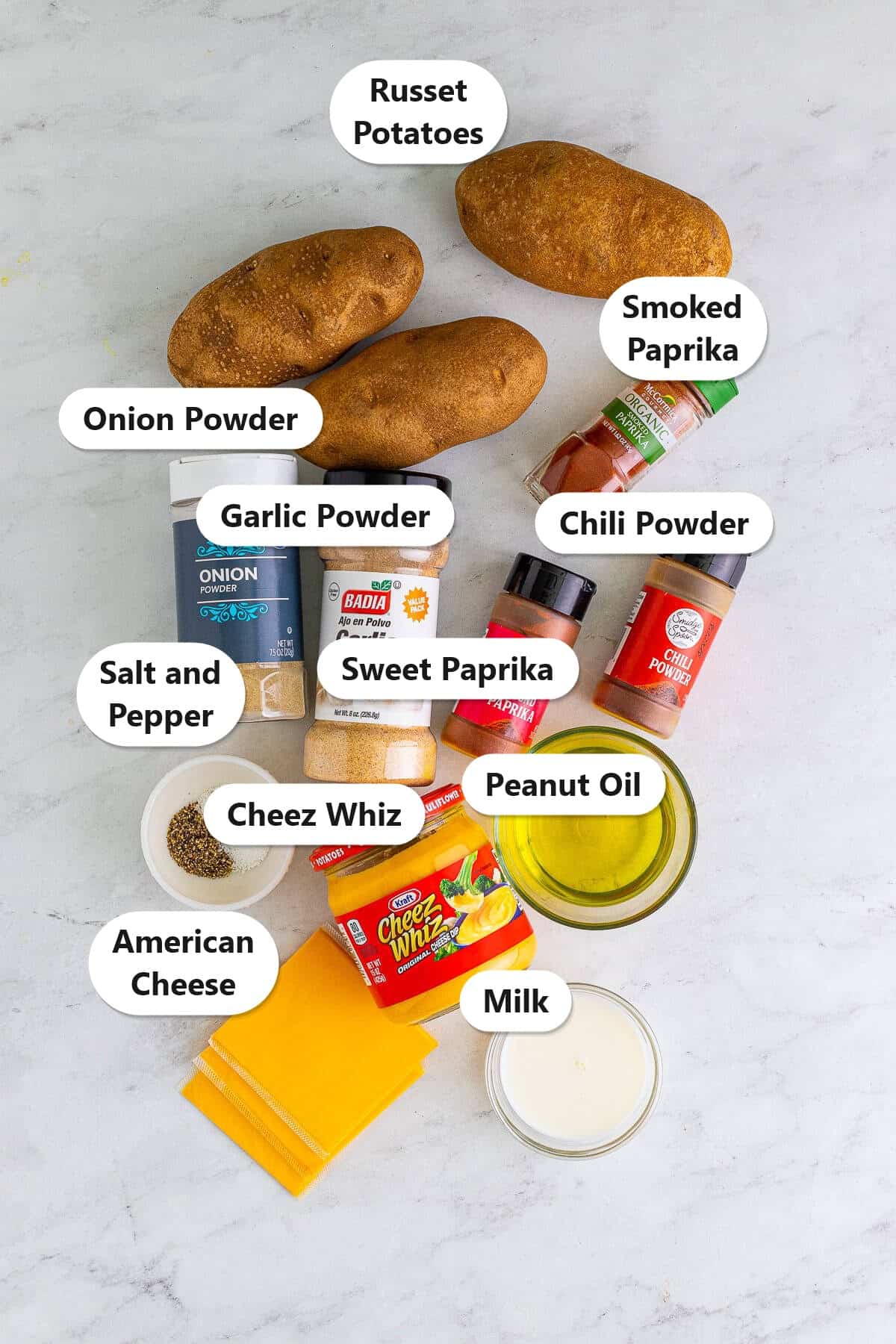 Labeled ingredients to make copycat Taco Bell nacho fries including russet potatoes, Cheez Whiz, American cheese, peanut oil, milk, and seasonings.