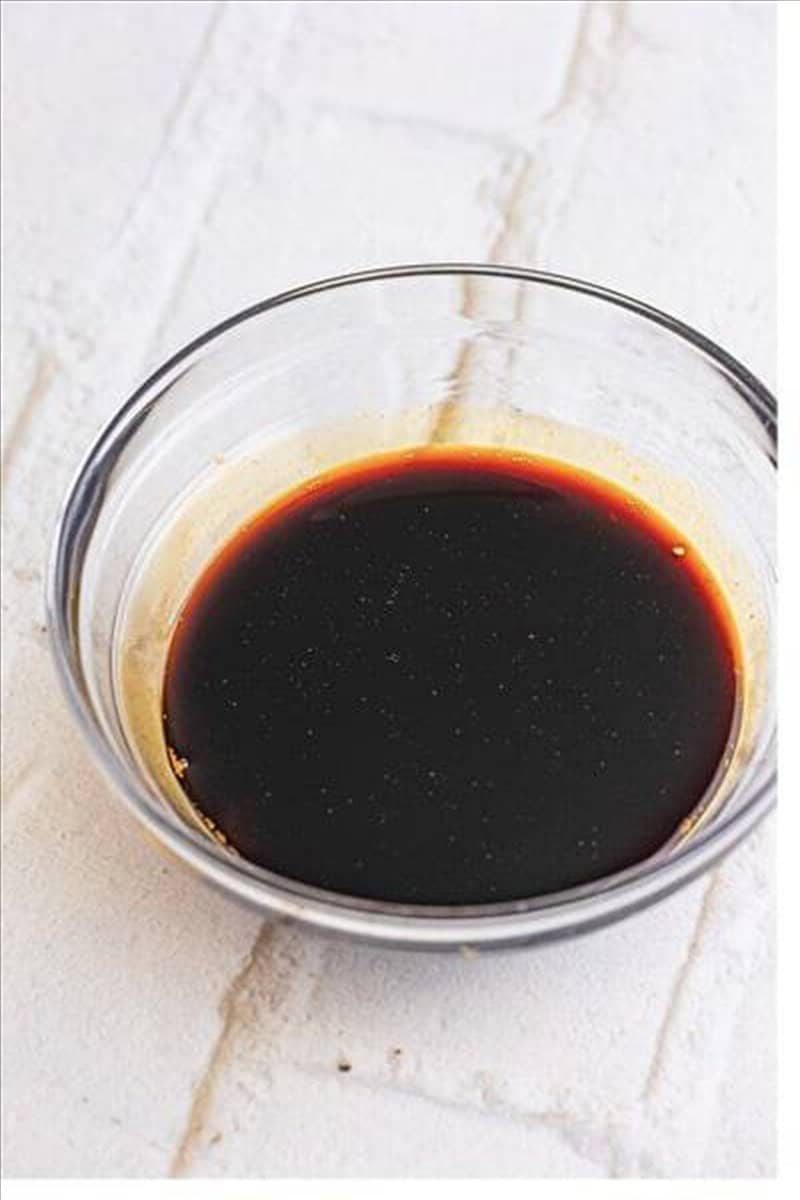 Pancit recipe sauce mixture of chicken stock, dark soy sauce, low sodium soy sauce, oyster sauce, and sugar in a small glass bowl.