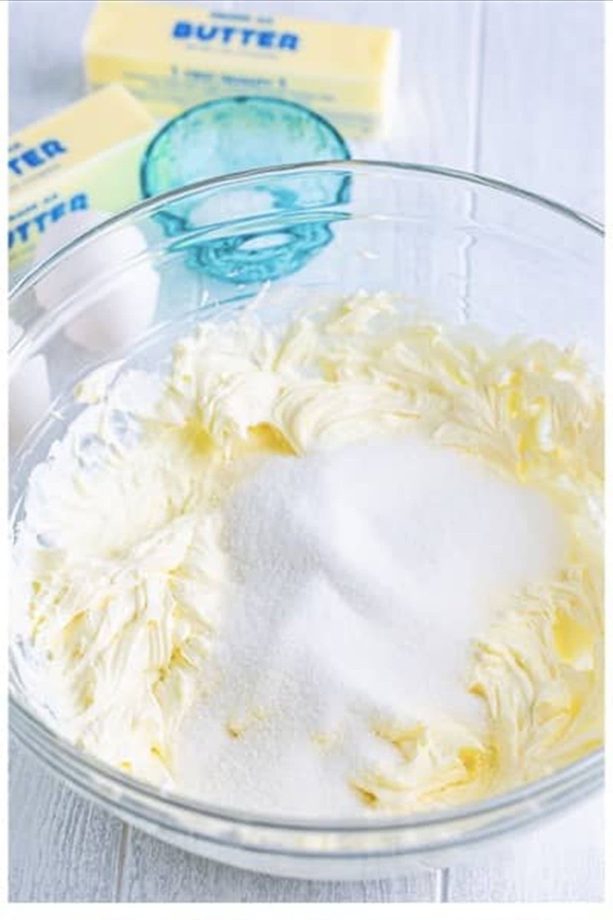 Cream cheese whipped smooth with sugar in a large glass bowl with an electric mixer for the pineapple cheesecake layer.