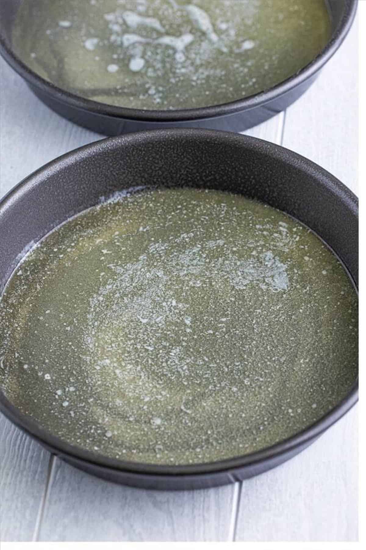 Melted butter divided equally between two 9-inch cake pans for the Pineapple Upside Down Cake topping.