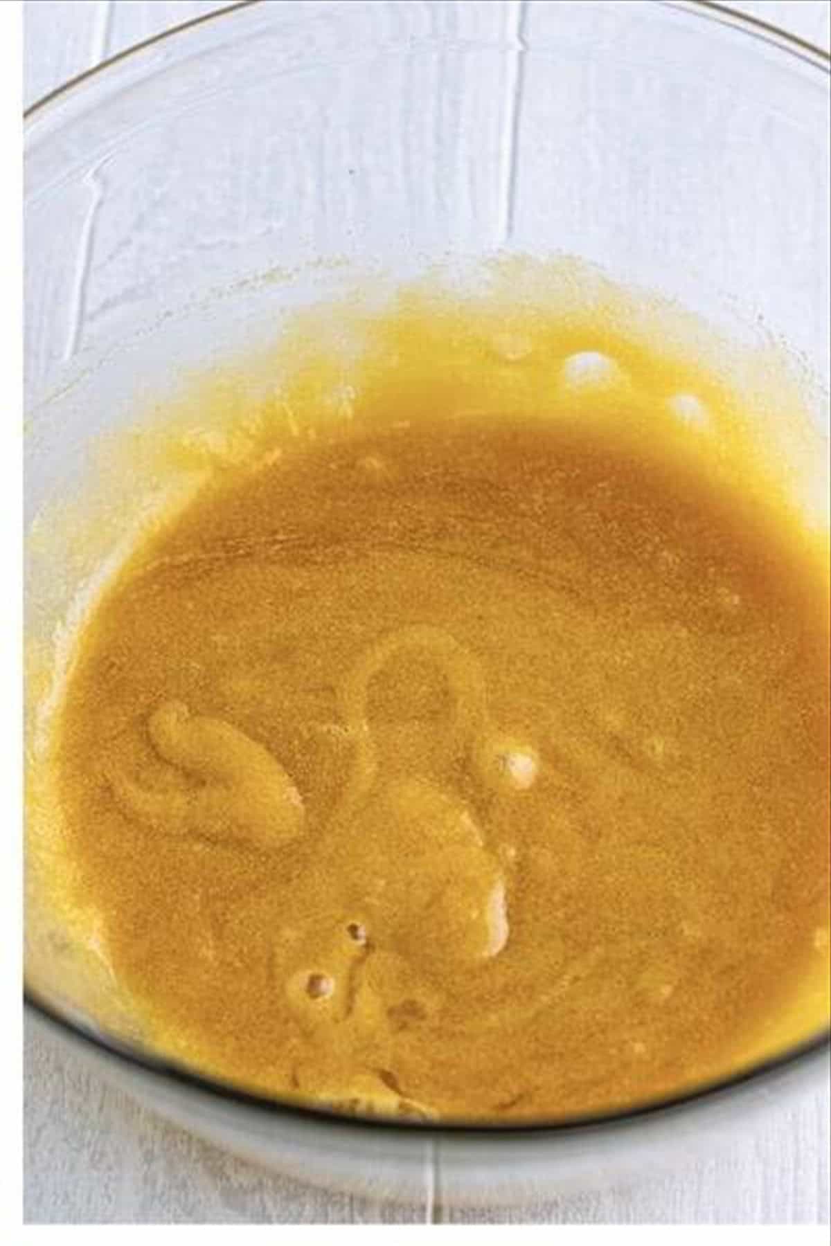 Melted butter whisked together with brown sugar and granulated sugar until smooth in a medium glass bowl.