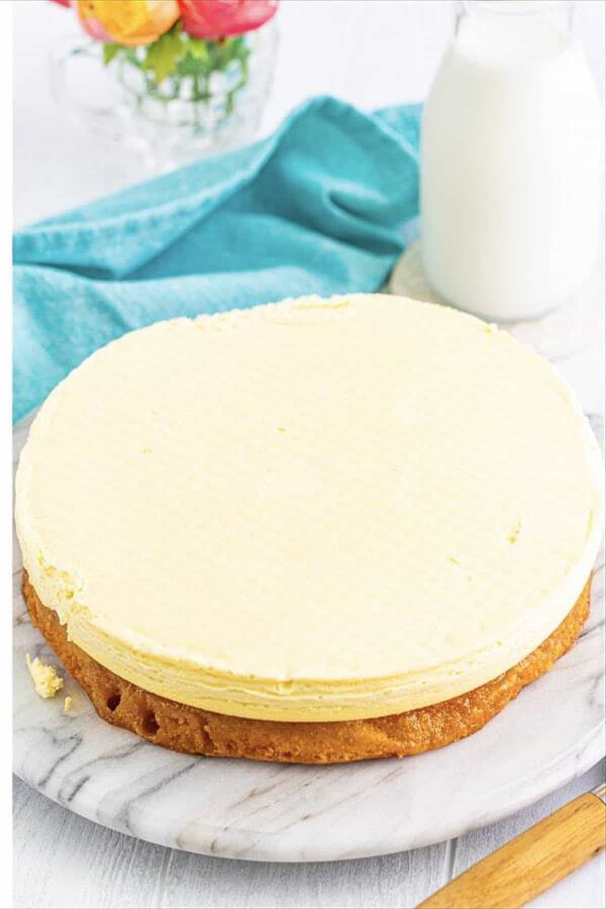 Pineapple cheesecake layer placed on top of the first Pineapple Upside Down Cake layer during assembly.