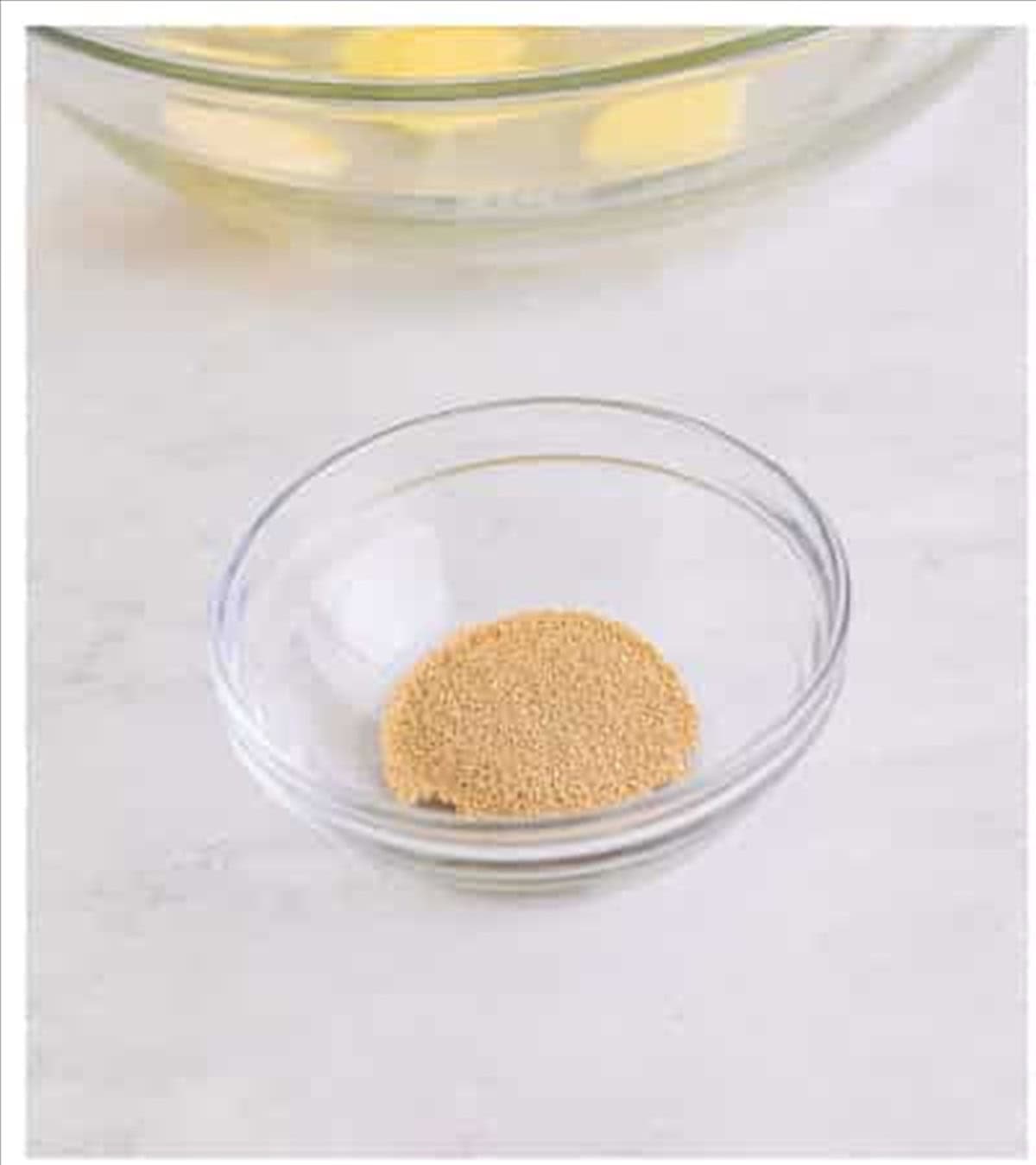 Active dry yeast in a glass bowl to start the Pizza Hut cheese sticks dough.