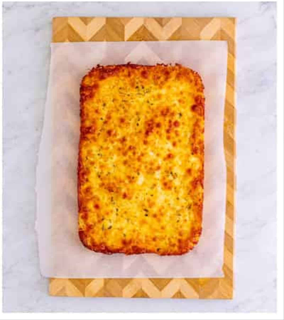Golden baked Pizza Hut cheese sticks cut into sticks on a cutting board.