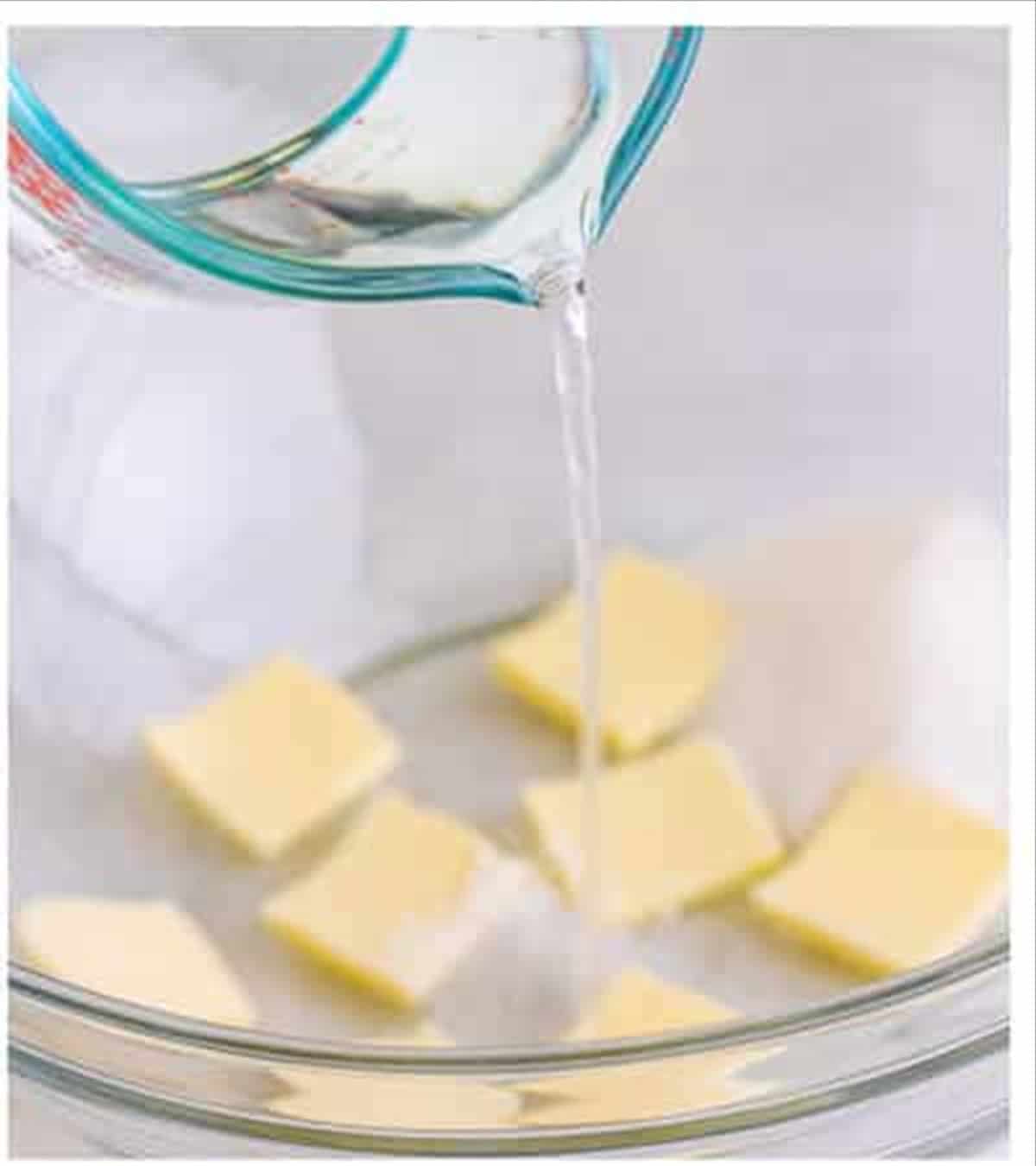 Warm water poured over butter cubes in a glass bowl for cheese sticks dough.