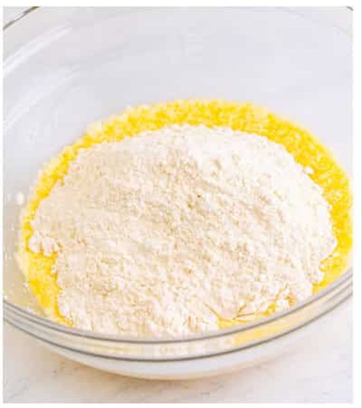 Flour added to the wet ingredients in a glass bowl for Pizza Hut cheese sticks.