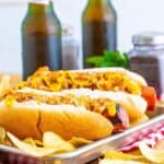 A pair of Polish Sausage Sandwich Recipe sandwiches with grilled sausage, caramelized onions, and yellow mustard on toasted hoagie rolls.