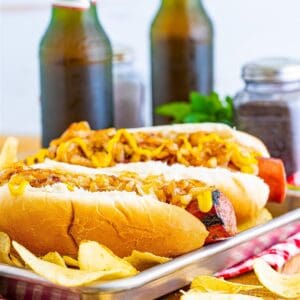 A pair of Polish Sausage Sandwich Recipe sandwiches with grilled sausage, caramelized onions, and yellow mustard on toasted hoagie rolls.