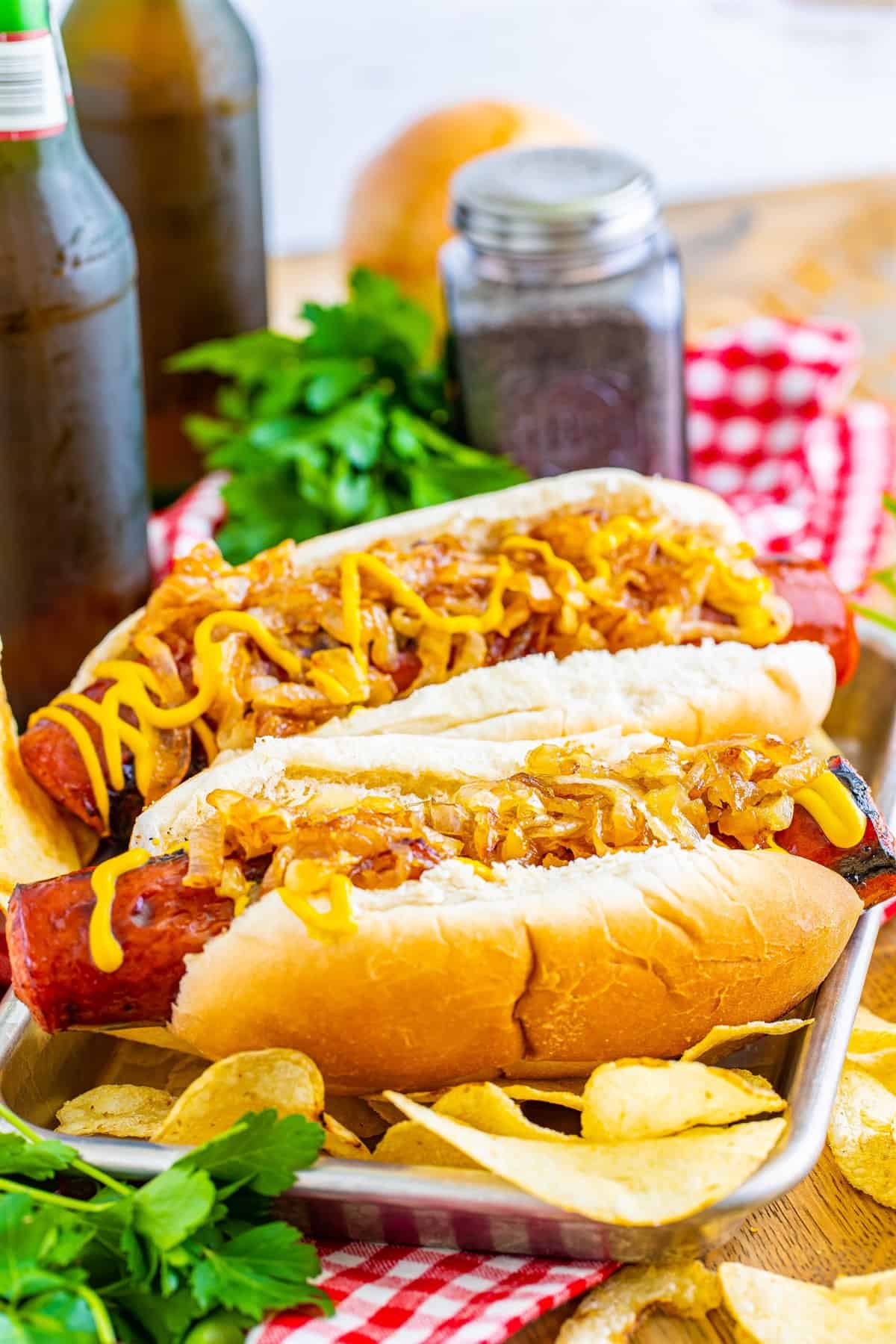 Two finished Polish Sausage Sandwich Recipe sandwiches with chips ready to serve.