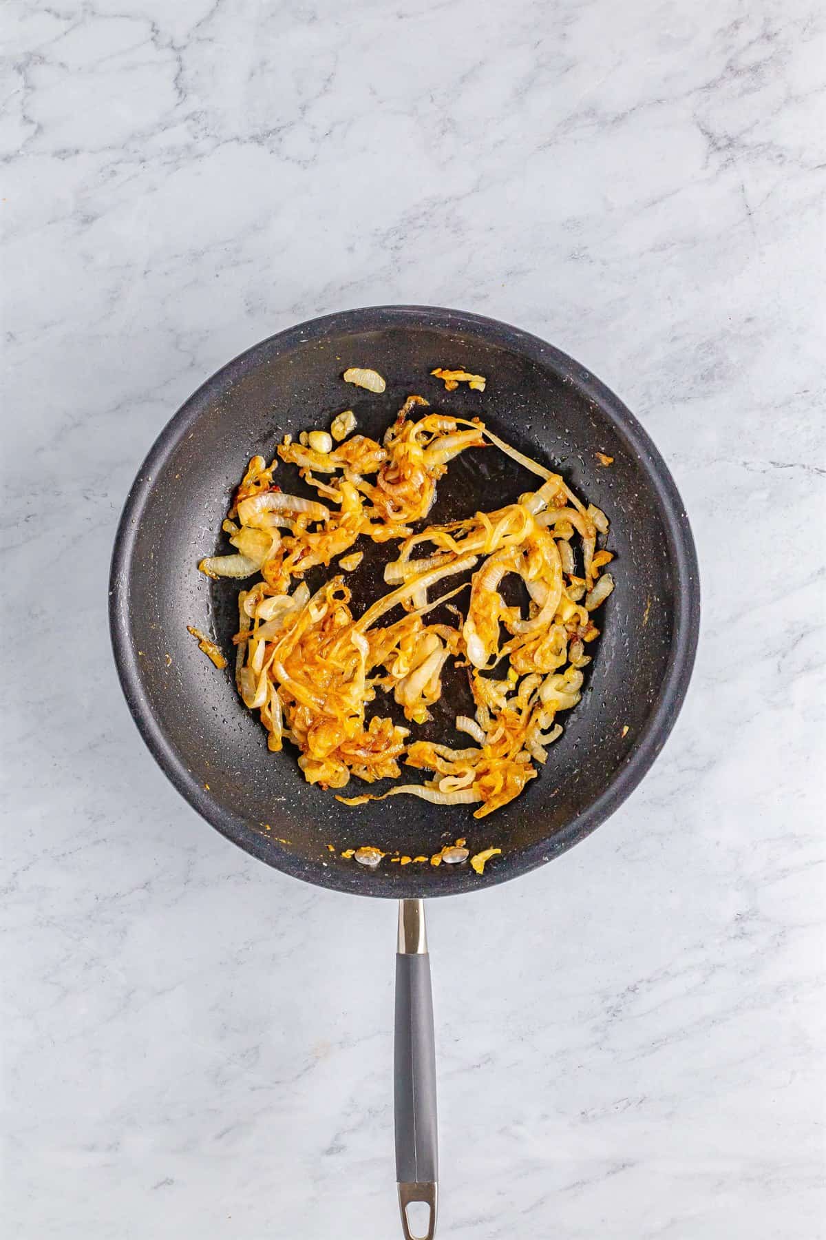 Golden caramelized sweet onions in a black skillet for the Polish Sausage Sandwich Recipe.