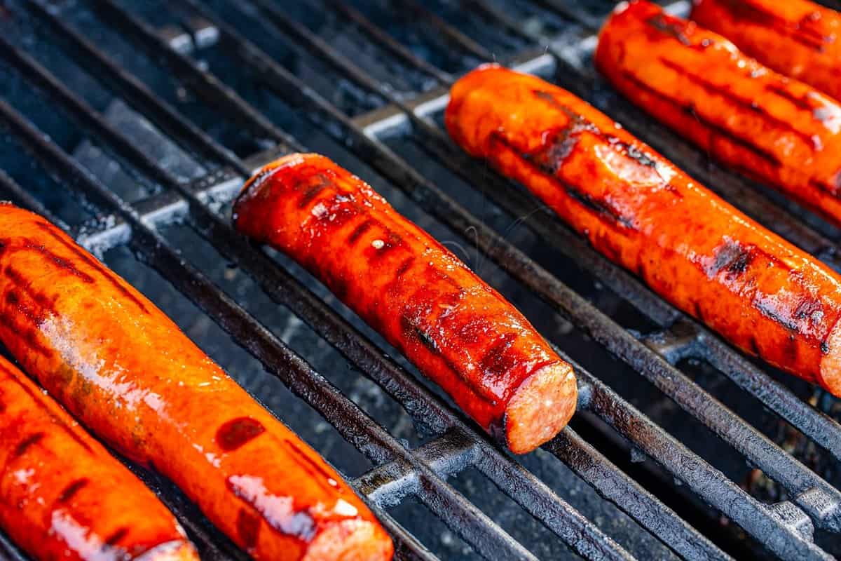 Polish sausages with deep grill char marks finishing on the grill for the Polish Sausage Sandwich Recipe.