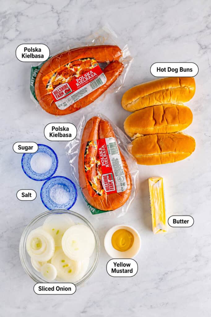 Polish sausage packages, hoagie rolls, sweet onions, butter, and yellow mustard arranged on a marble counter for the Polish Sausage Sandwich Recipe.
