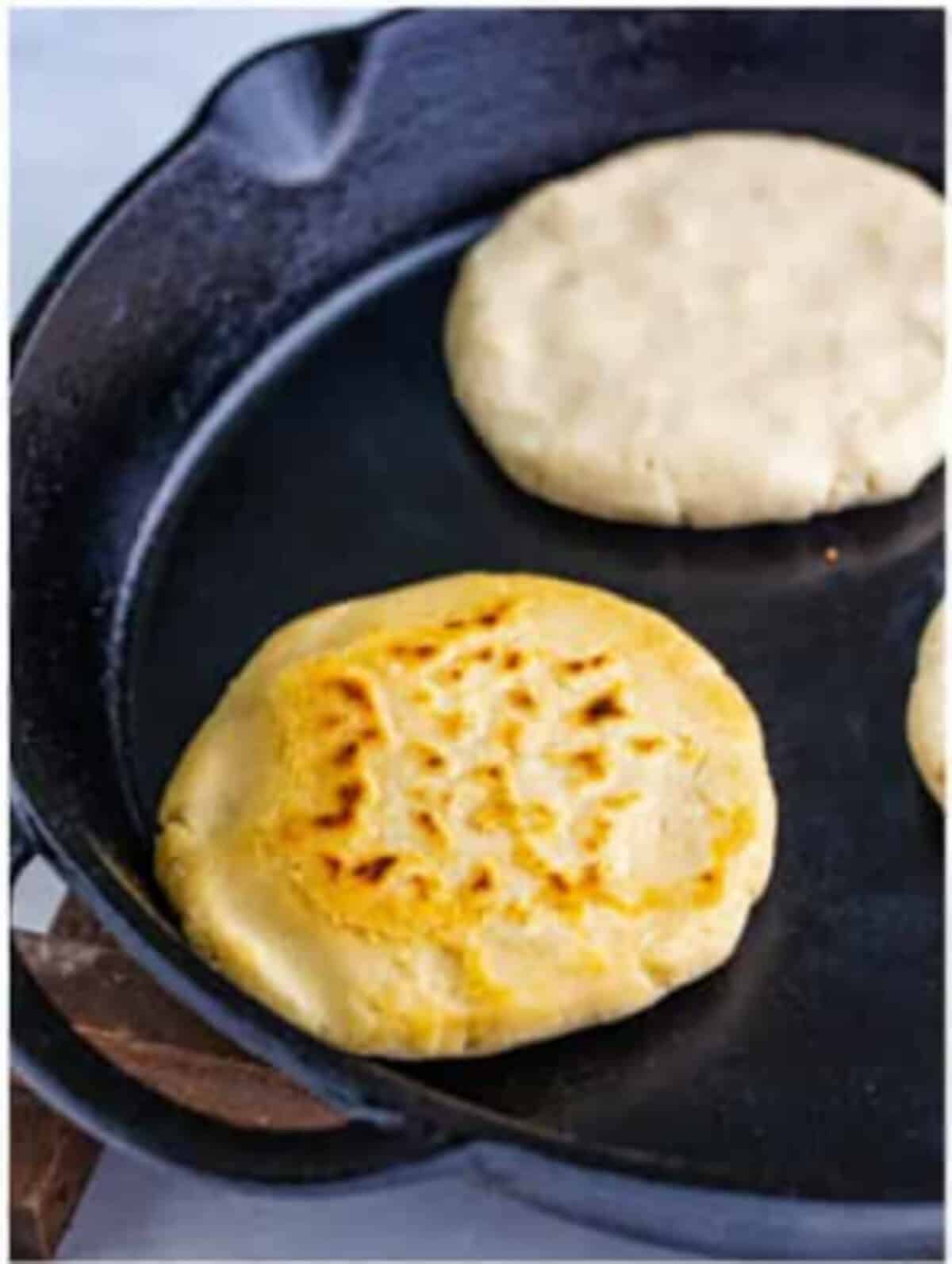 Finished pupusa torn open showing melty cheese inside, the finale shot of a Pupusas Recipe.