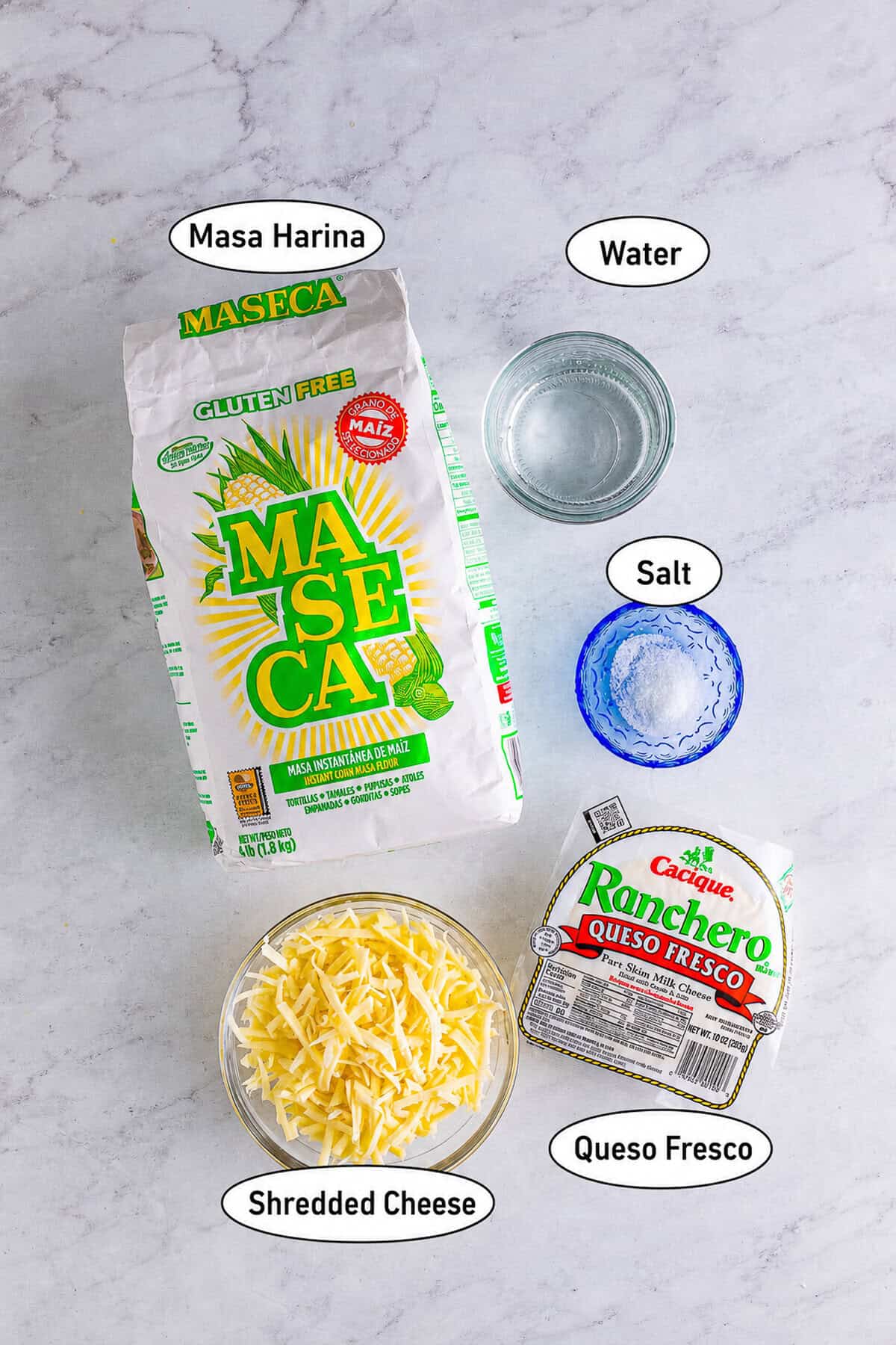 Five ingredients needed to make a Pupusas Recipe arranged in bowls including masa harina, water, salt, mozzarella, and queso fresco.