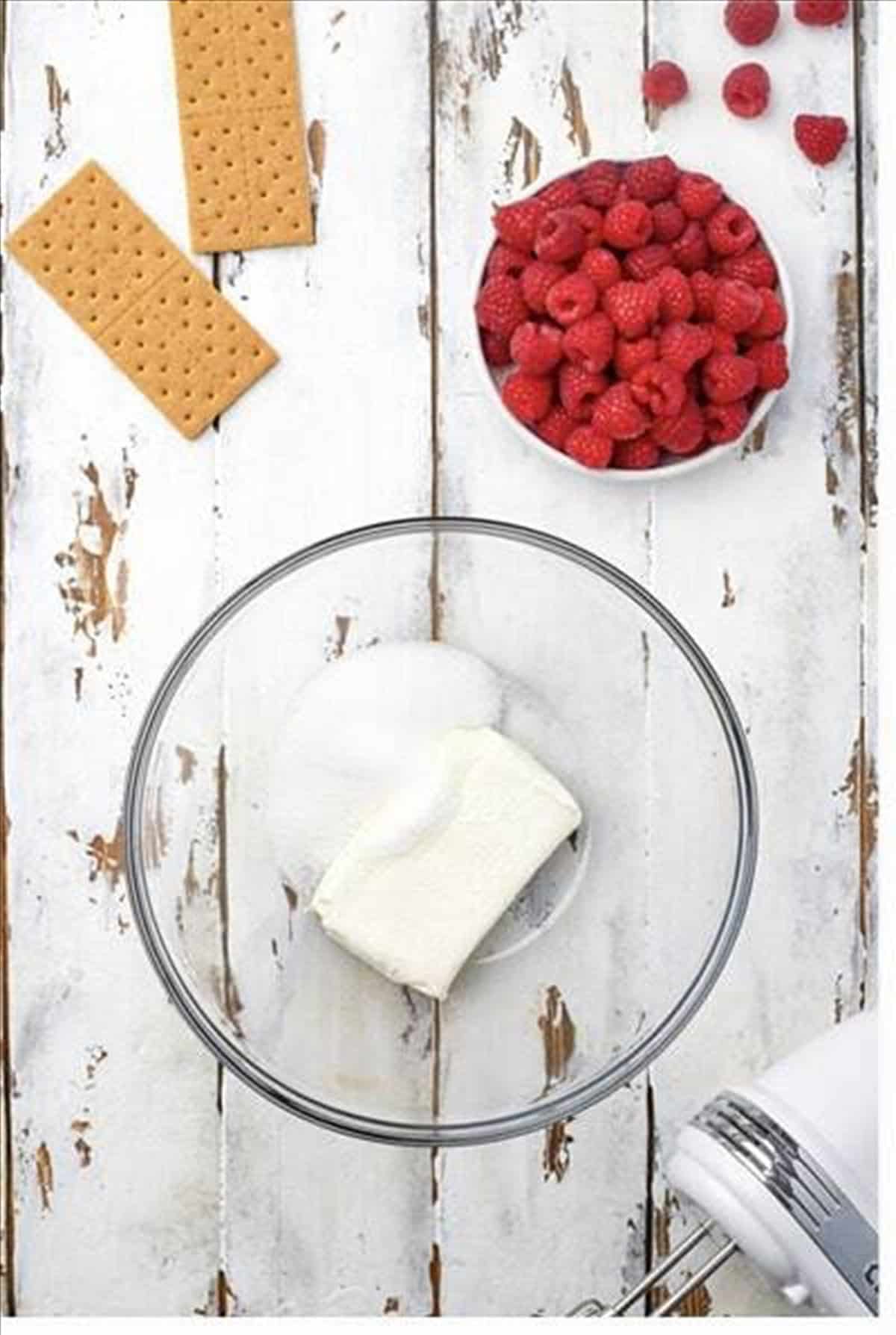 Cream cheese and sugar in a bowl to start the raspberry cheesecake bites.