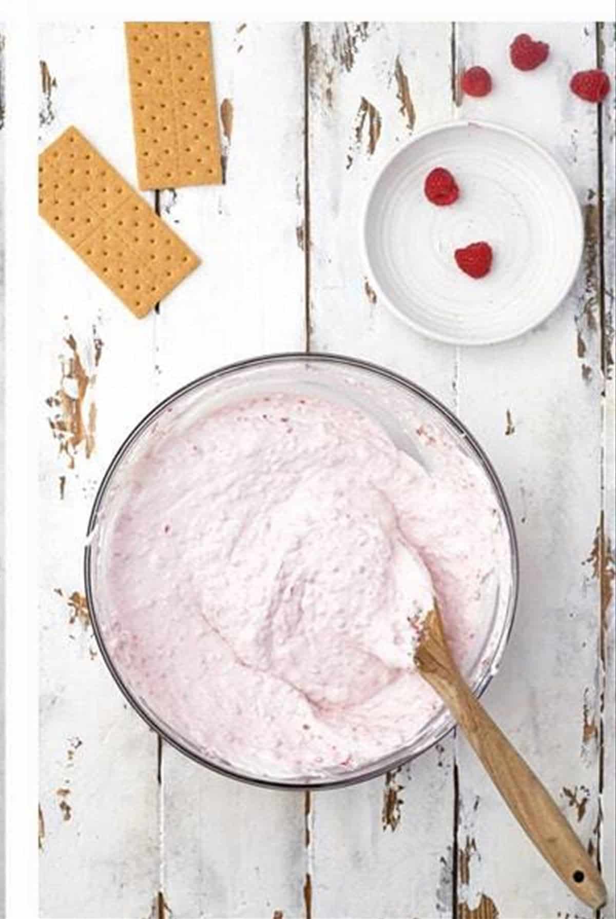 Whipped topping folded into the light pink raspberry cheesecake filling.