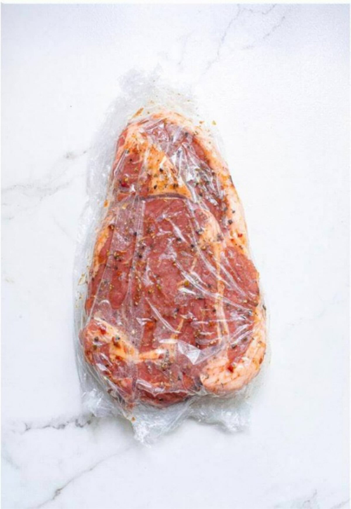 Seasoned ribeye steak resting at room temperature for 30 minutes before hitting the grill.