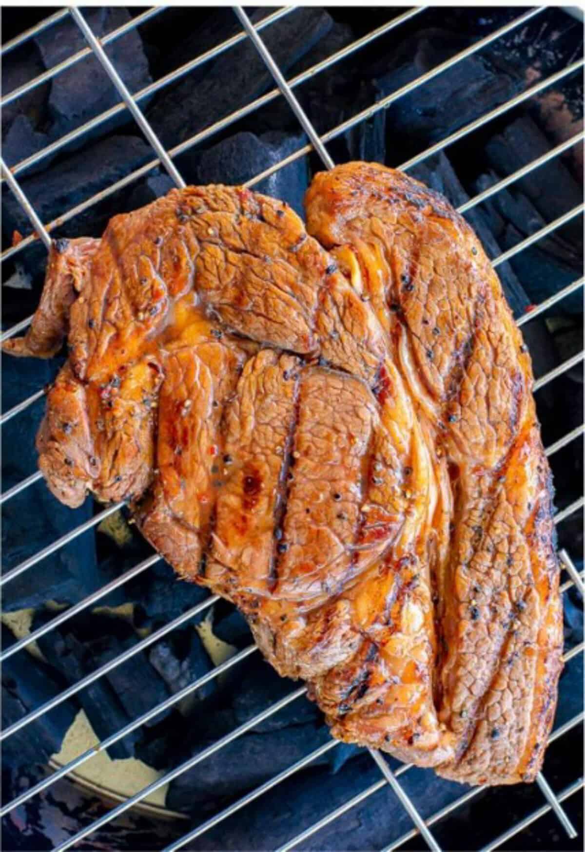 Marinated ribeye steak searing over high heat on the grill with a perfect char crust forming.