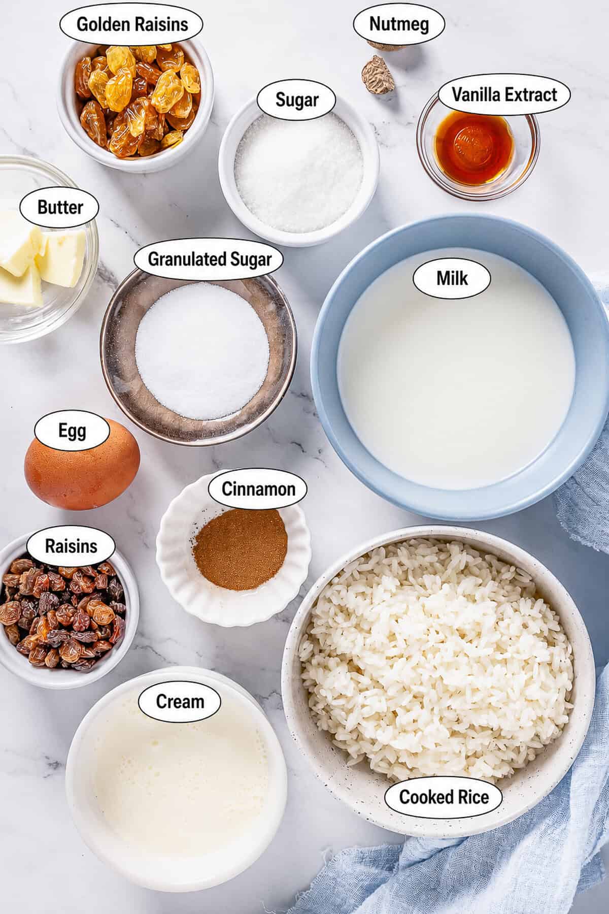 Labeled ingredients for Rice Pudding Recipe including cooked white rice, milk, heavy cream, eggs, sugar, raisins, butter, vanilla, cinnamon, and nutmeg.