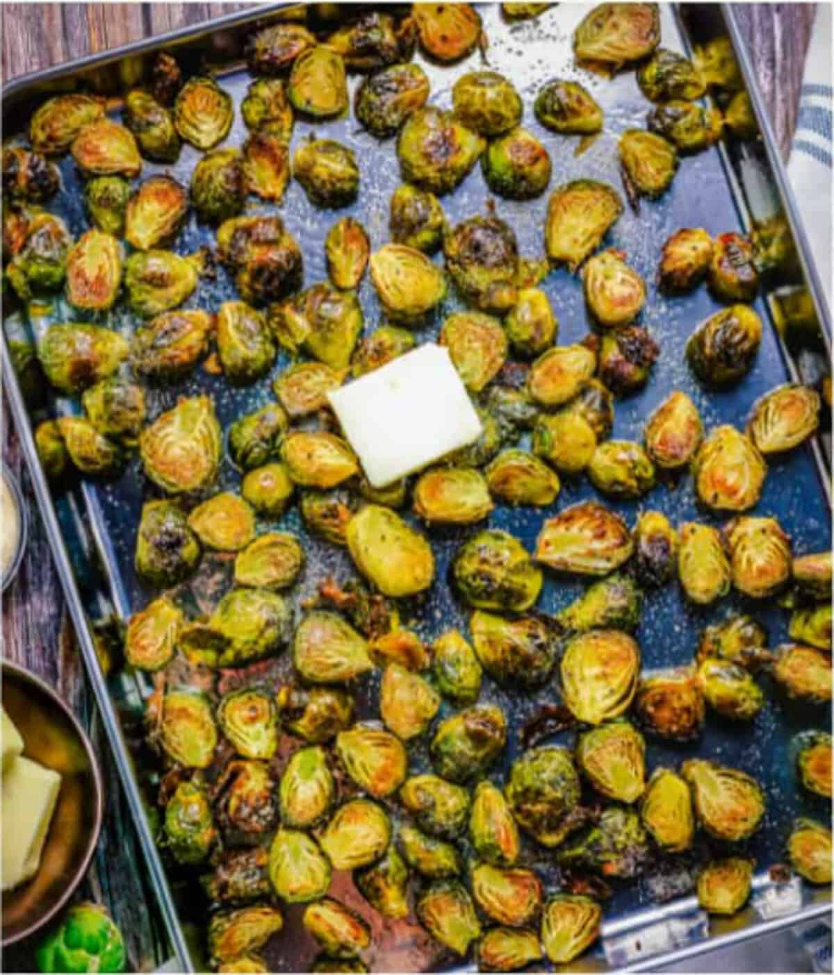 Finished Easy Oven Roasted Brussel Sprouts Recipe tossed with melted butter and garlic powder in the warm sheet tray, ready to plate as a side dish.