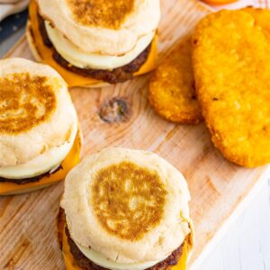 A homemade Sausage Egg McMuffin Recipe sandwich with melted American cheese, sausage patty, and round egg on a toasted English muffin.