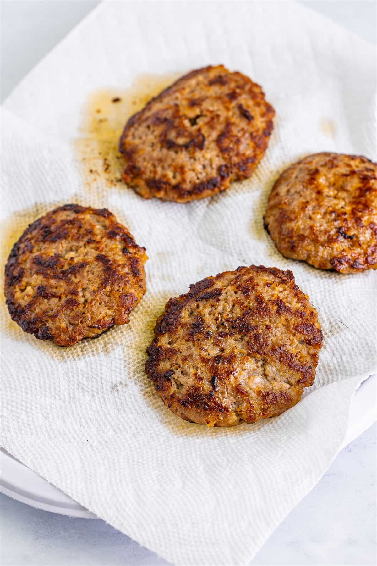 Breakfast sausage patties cooking in a black skillet for the Sausage Egg McMuffin Recipe.