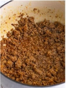 Browning ground pork sausage with cumin, pepper, and paprika in a Dutch oven for Sausage Rice Recipe.