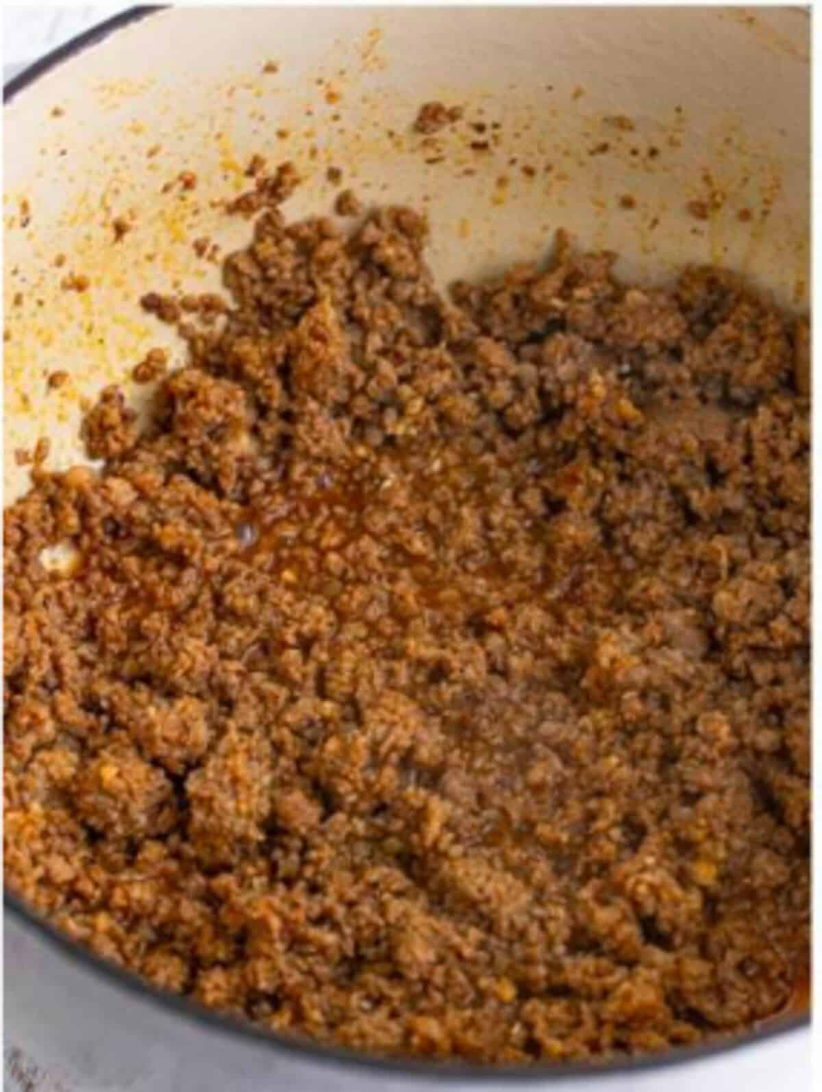Browning ground pork sausage with cumin, pepper, and paprika in a Dutch oven for Sausage Rice Recipe.
