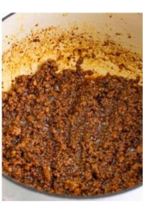 Adding minced garlic to the sausage mixture for Sausage Rice Recipe.