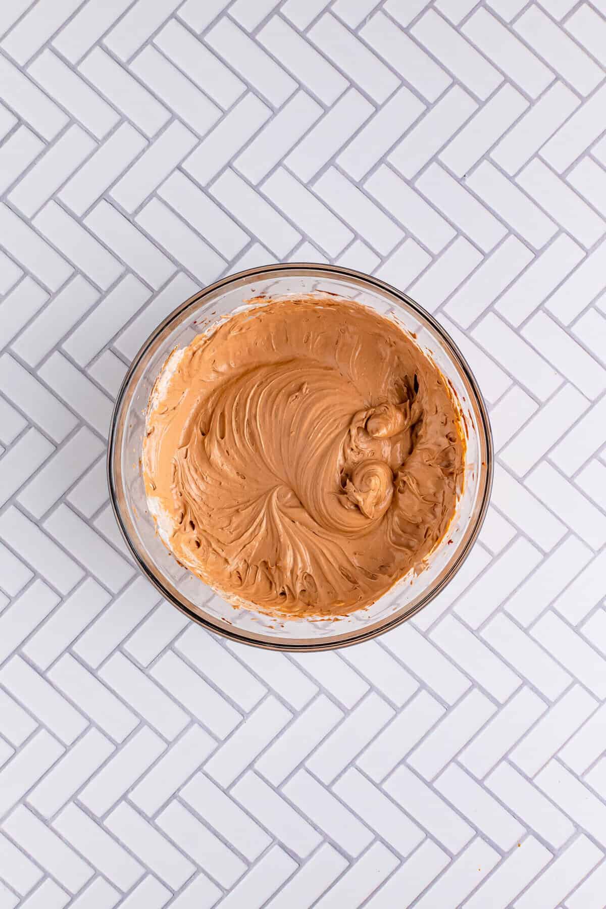 Whipped topping being folded into chocolate pudding mixture for the Italian Love Cake Recipe topping layer.