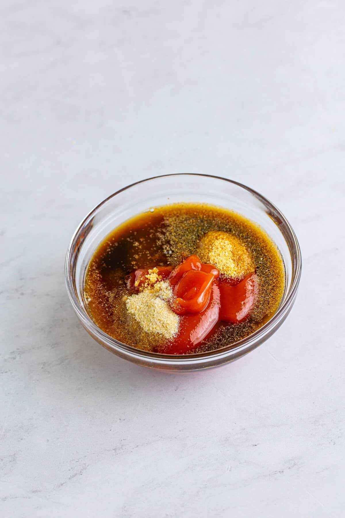 Arbys red sauce ingredients ketchup brown sugar vinegar Worcestershire and garlic powder in a small glass bowl ready to whisk.