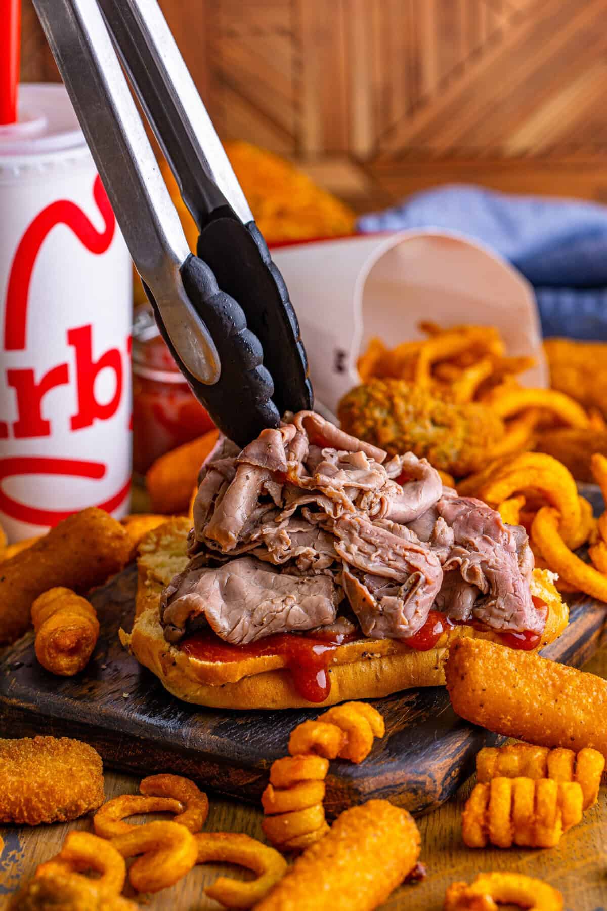 Cheddar cheese sauce poured over warm shaved roast beef on a toasted onion bun for an Arbys beef and cheddar copycat.
