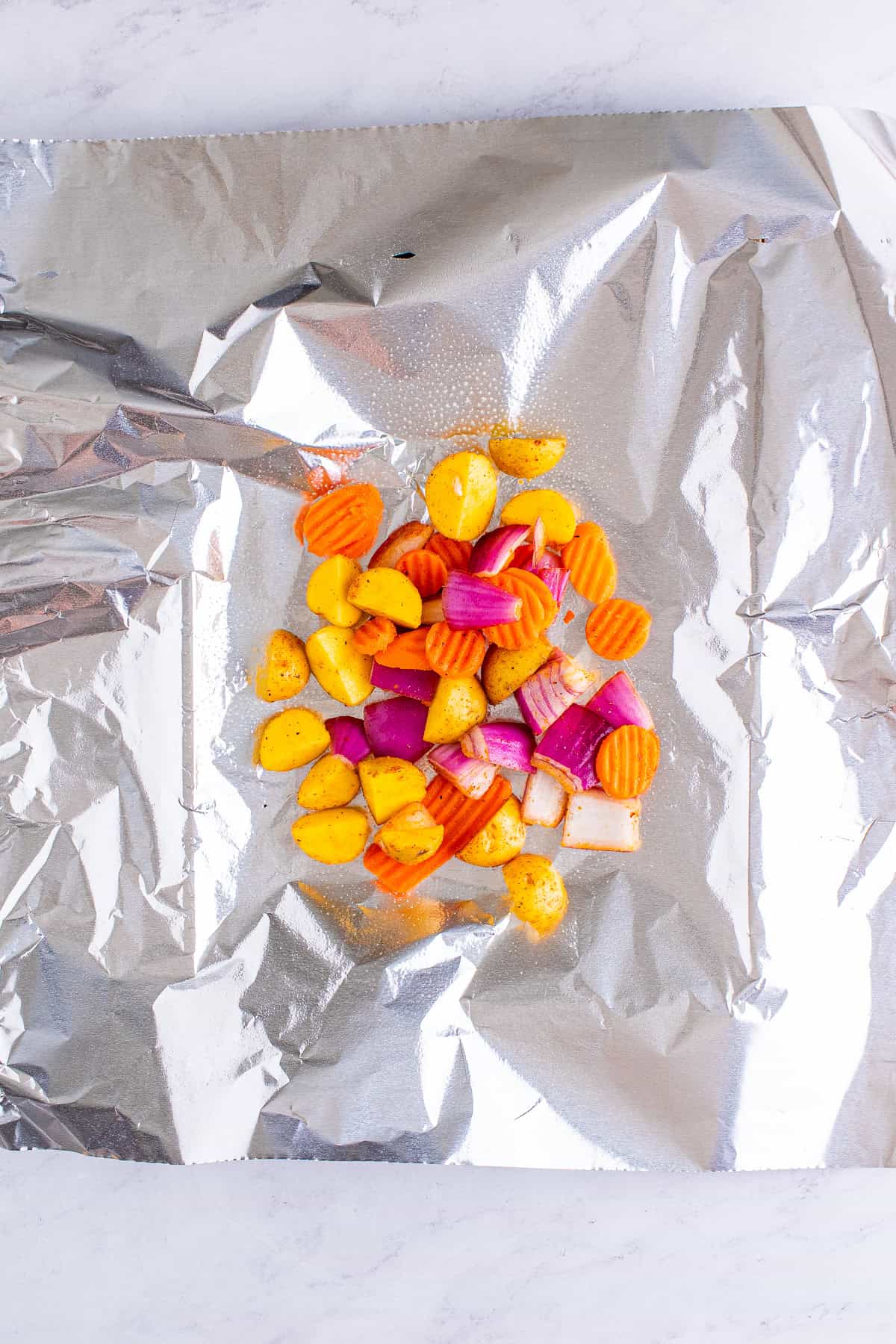 Seasoned vegetables placed in the center of a foil sheet