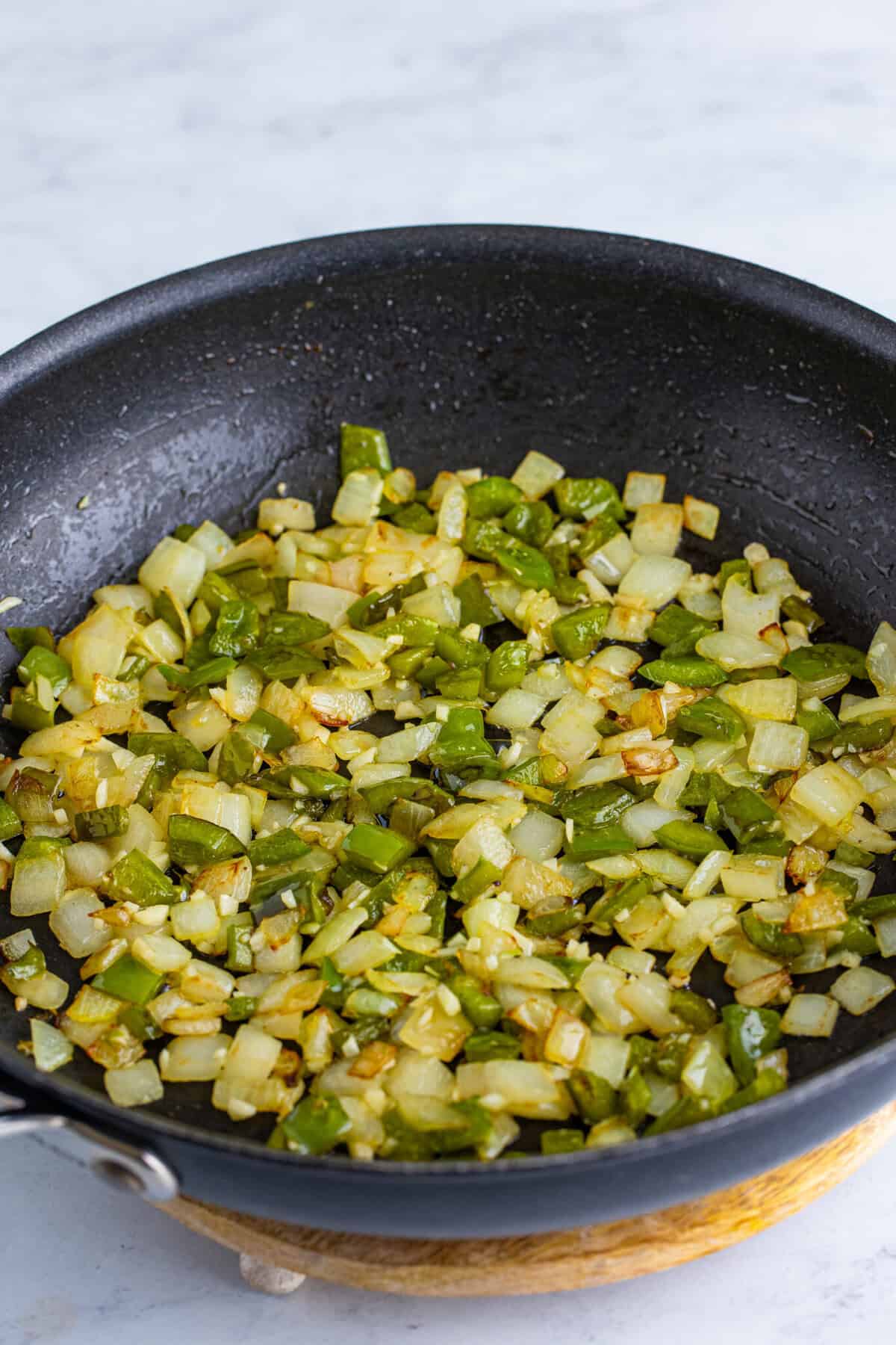 Diced onion and green bell pepper cooked down and lightly browned in a large nonstick skillet for homemade Dr Pepper sloppy joes.