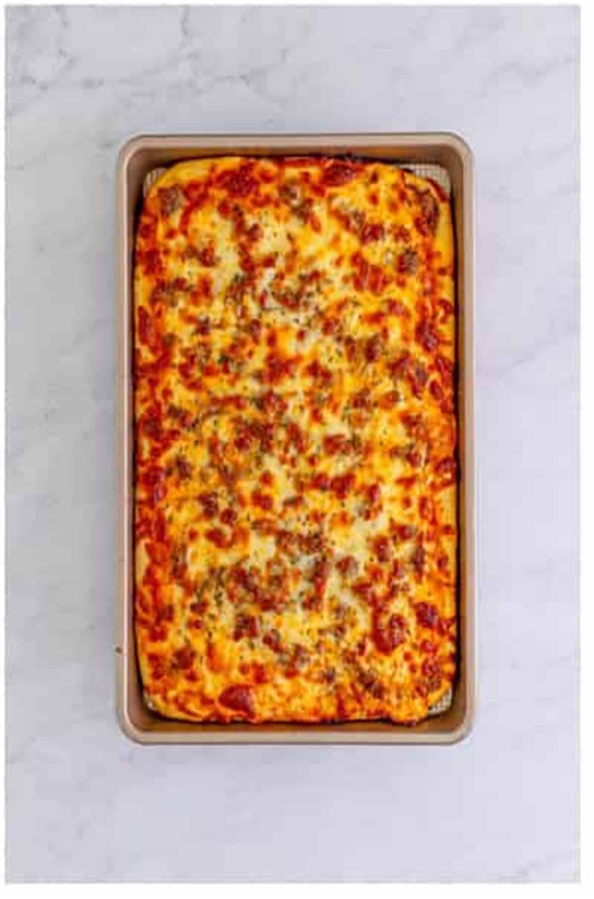 Golden bubbly baked Sheet Pan Pizza fresh from the oven in the rimmed sheet pan for The Best Sheet Pan Pizza Recipe.