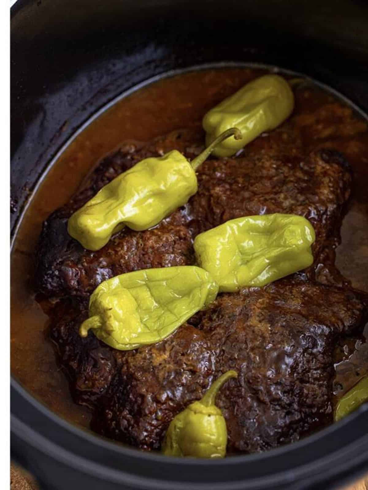 Tender Slow Cooker Cube Steak finished cooking in the crock pot with pepperoncini and gravy.