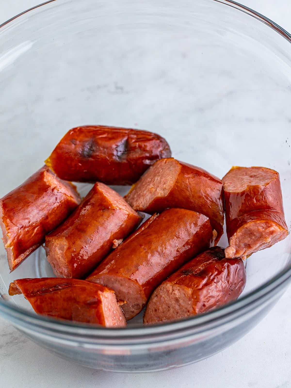 Smoked kielbasa cut into pieces in a glass bowl.