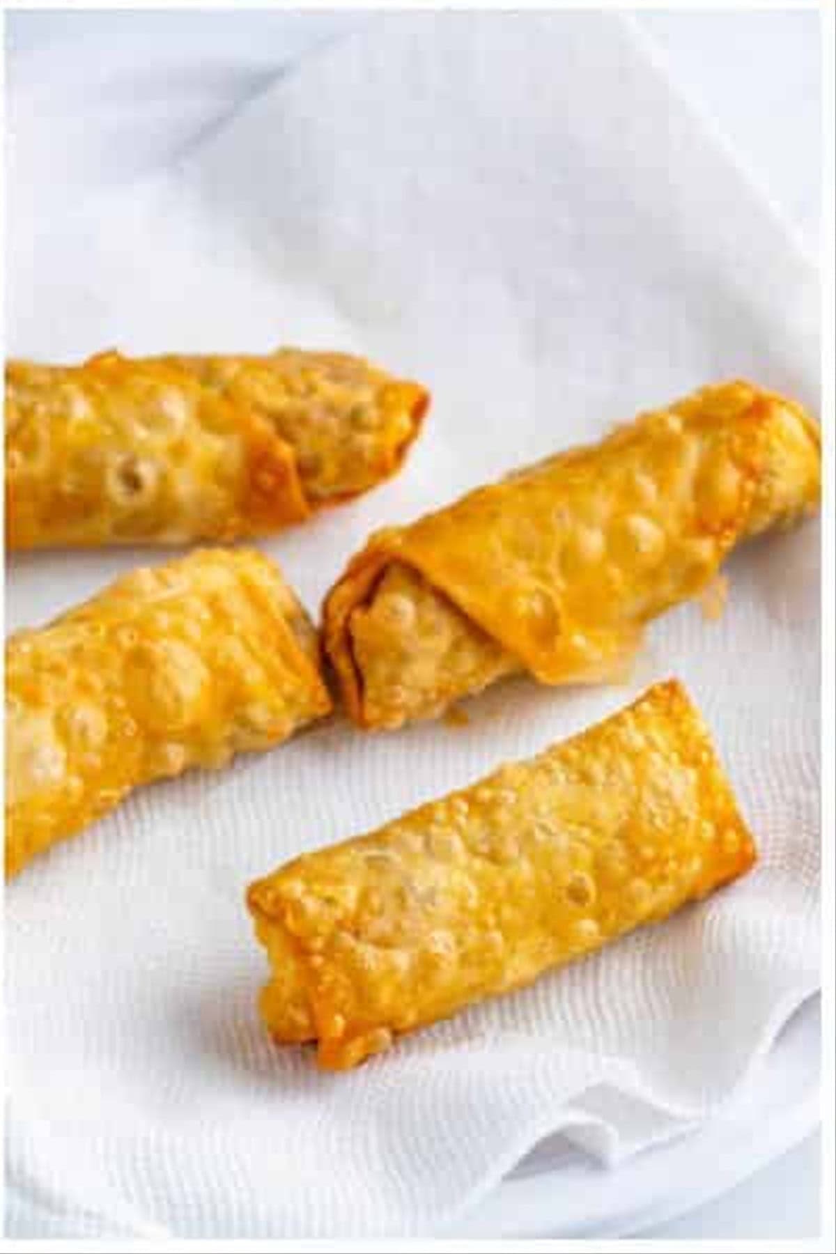 Golden brown crispy Southwest Egg Rolls draining on a paper-towel-lined plate after frying.