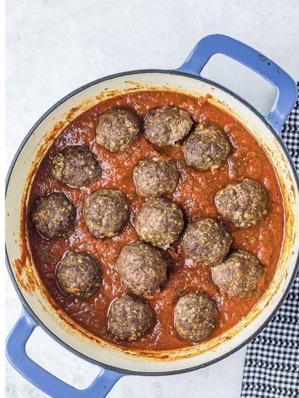 Baked meatballs added into the simmering spaghetti sauce.