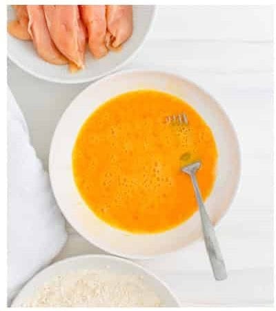 Eggs and Frank hot sauce whisked together in a shallow bowl for the wet bath for Buffalo Chicken Tenders.
