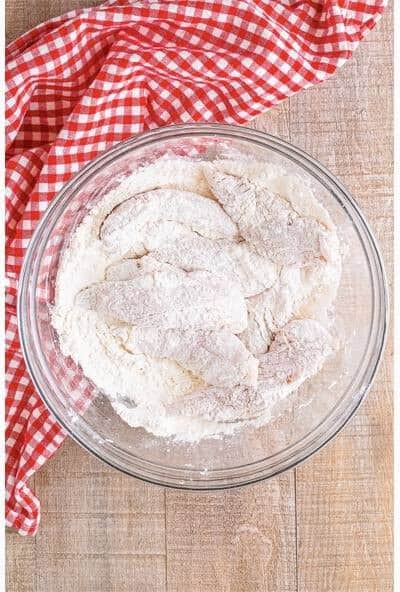 Seasoned chicken tenders dredged in the seasoned flour for the Battered Chicken Tenders coating.