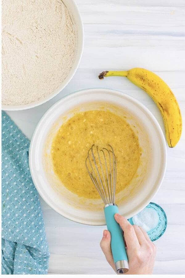 Mashing ripe bananas with eggs, melted butter, oil, milk, and vanilla for the wet ingredients.