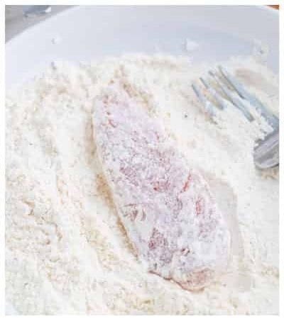 Coating raw chicken tenders in the seasoned flour dredge before the egg wash.