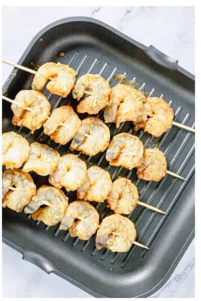 Marinated shrimp threaded onto wooden skewers ready for the grill.