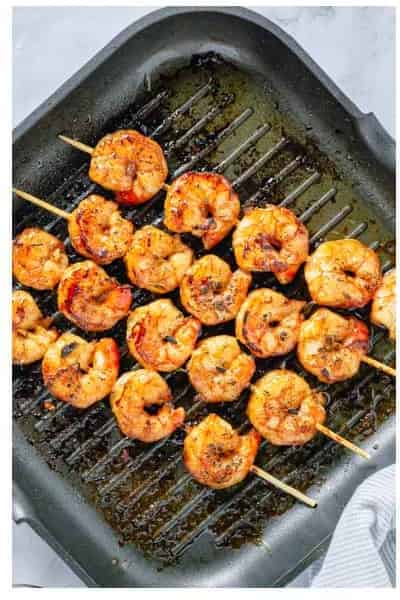Asian Marinated Grilled Shrimp Skewers grilling on a hot grill pan with char marks.
