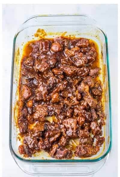 BBQ sauce poured over the partially cooked burnt ends and stirred until every piece is coated.