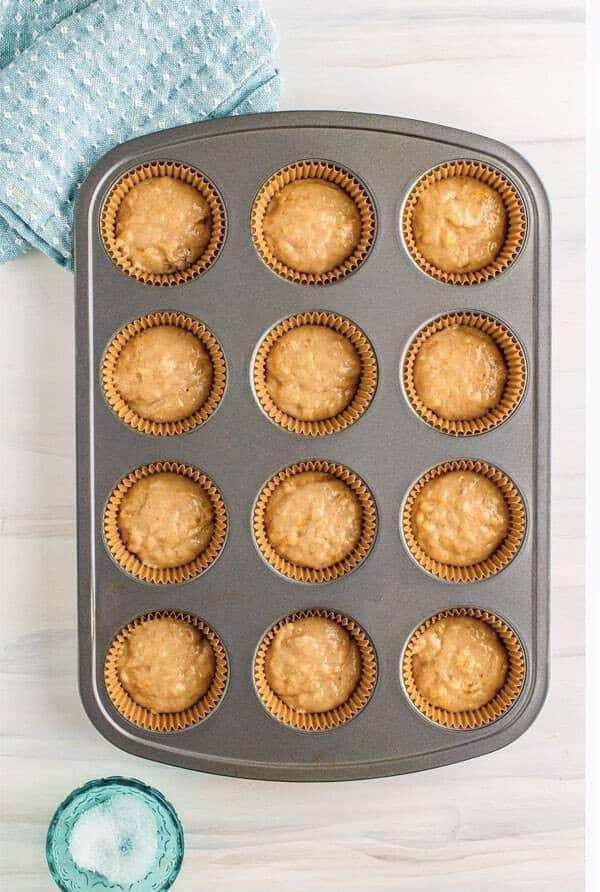 Filling muffin tin with banana batter, cream cheese dollop in center, topped with more batter.