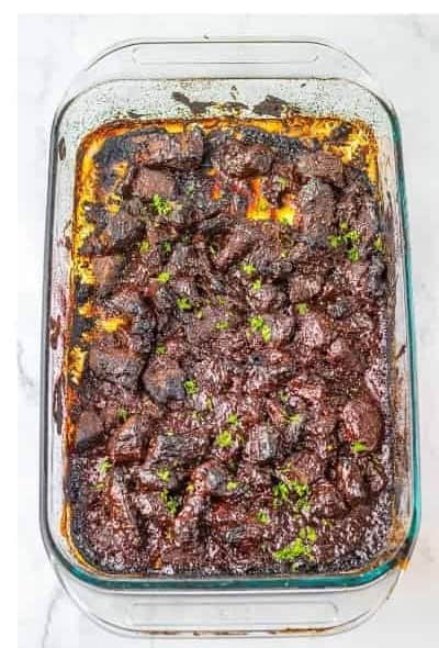 Finished Chuck Roast Burnt Ends with sticky caramelized BBQ glaze and fresh parsley garnish in the baking dish.