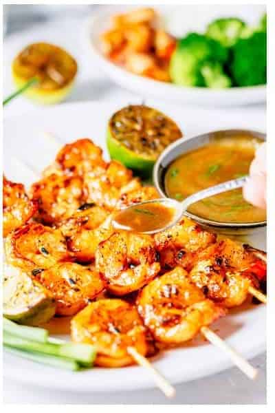 Plated Asian Marinated Grilled Shrimp Skewers drizzled with reduced glaze served with broccoli and rice.