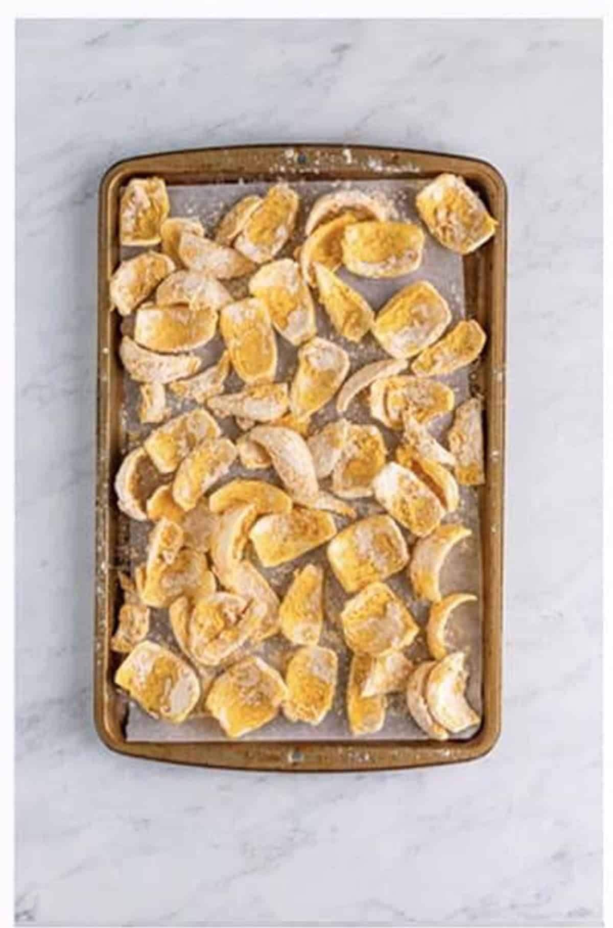 Return petals to seasoned flour and arrange on a sheet pan for Crispy Onion Petals Recipe.